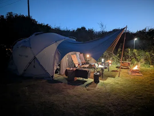 SEKACAMP G-MAX TENTにタープを接続した夜の全景。ランタンの灯りに照らされたキャンプサイト